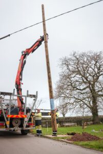 Worker lifting Polesaver protected utility pole off truck